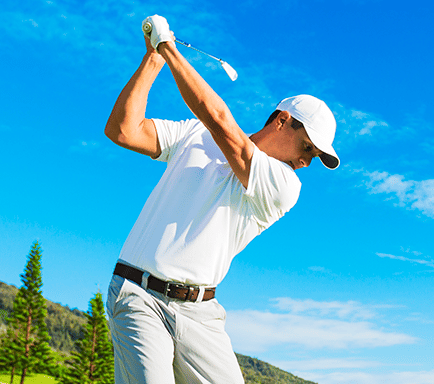 Golfer hitting golf ball with sky background
